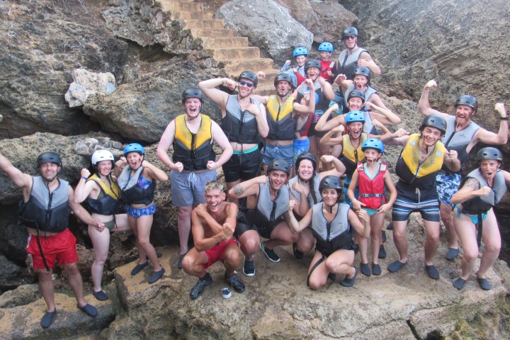 Group of people in life vests and helmets posing on rocks.